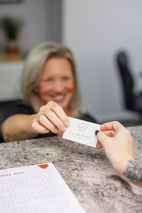 Front desk staff giving a patient a business card at Clarendon Family Dentistry