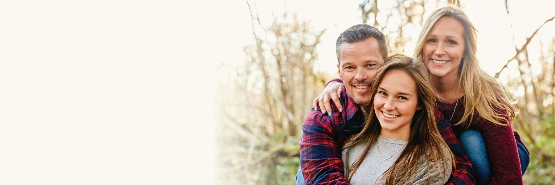 A daughter and her parents smiling in a field