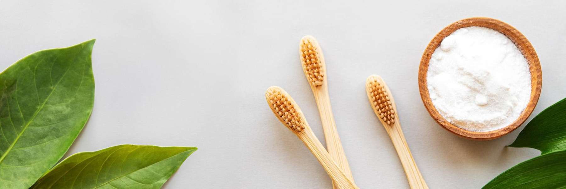 Three toothbrushes and a bowl of baking soda