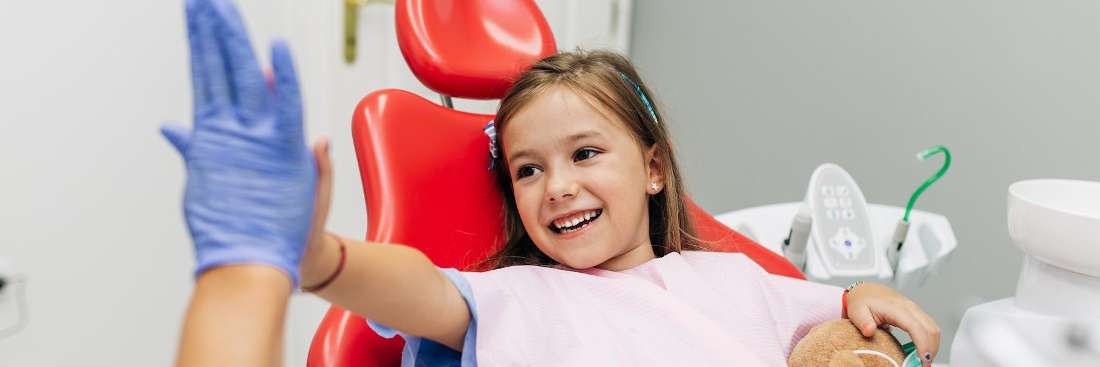 A smiling child giving her dentist a high five after a dental exam