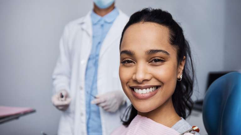 A smiling woman getting a dental exam in 2025
