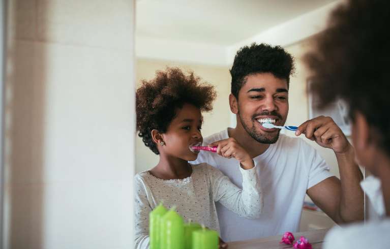 A father and his daughter brushing their teeth