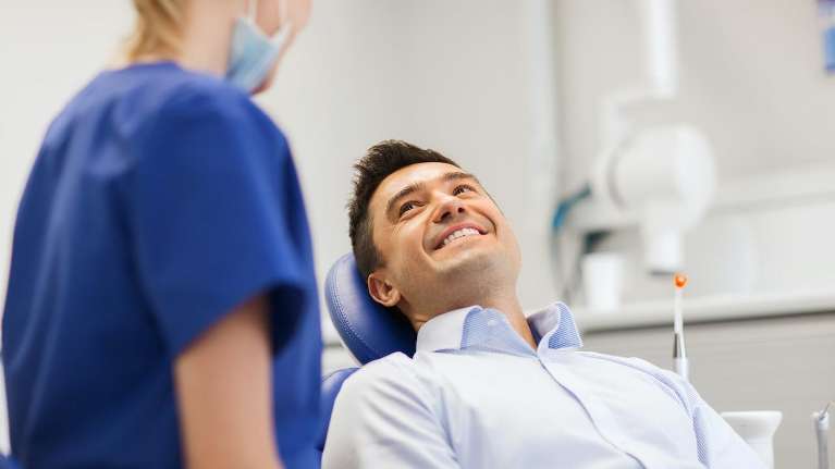 A smiling man talking to his dentist