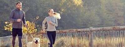 A couple jogging with their dog